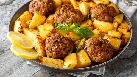 Chiftele grecești la cuptor cu cartofi. Rețeta aromată care transformă o masă simplă într-un festin