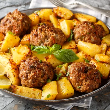 Chiftele grecești la cuptor cu cartofi. Rețeta aromată care transformă o masă simplă într-un festin